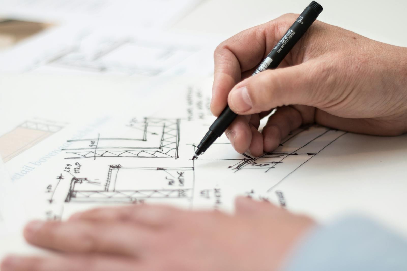 MAESGAR Pozuelo de Alarcón Close-up of hand drawing intricate technical designs on blueprint with pen, ideal for engineering or architecture themes.