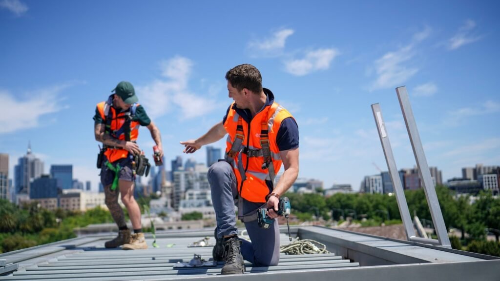 Contactar MAESGAR Pozuelo Construction workers wearing safety gear are on a rooftop.